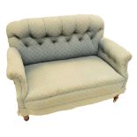 A small late Victorian button backed upholstered settee on ring turned legs.