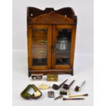 An Edwardian oak smoker's cabinet with a pair of glazed doors enclosing fitted interior with three