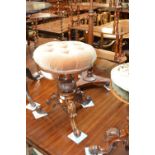 A Victorian walnut revolving piano stool with buttoned upholstered circular seat above carved