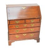 A late George III oak and mahogany crossbanded bureau of small proportions,