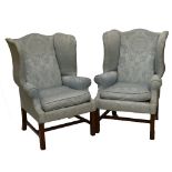 A pair of reproduction Georgian style upholstered wing back armchairs on square supports.
