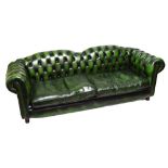 A green leather upholstered two seater Chesterfield sofa with buttoned back and arm rests,