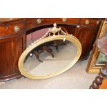 An early 20th century gilt oval husk and urn decorated wall mirror, height 86, width 100cm.