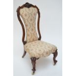 A Victorian rosewood framed upholstered nursing chair with scroll and floral carved back,