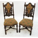 A pair of ornate carved stained beech hall chairs with upholstered backs and seats.