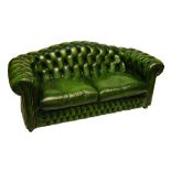 A green leather upholstered two seater Chesterfield sofa with buttoned back, arm rests and front,