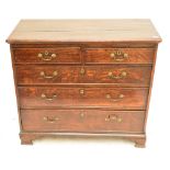 A late George III oak chest of two short and three long graduated drawers raised on ogee bracket