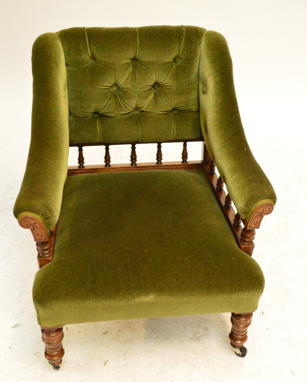 A Victorian walnut framed upholstered gentleman's chair with buttoned and spindle decorated back