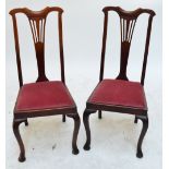 A pair of Edwardian walnut salon chairs with pierced splay backs and cabriole legs.