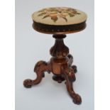 A Victorian walnut circular revolving piano stool with floral wool work upholstered seat above