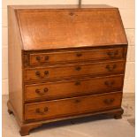 A late c1900 oak and inlaid bureau with fitted interior and four drawers,