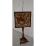 A 19th century walnut pole screen decorated with floral tapestry on turned base and three paw