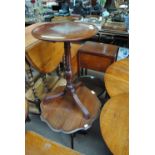 A circular mahogany tripod table with shaped top,