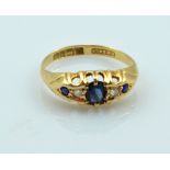 An 18ct yellow gold sapphire and diamond dress ring with central sapphire flanked by two small