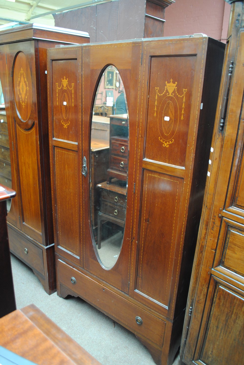 An Edwardian inlaid wardrobe centred with an oval mirror, width 94cm.