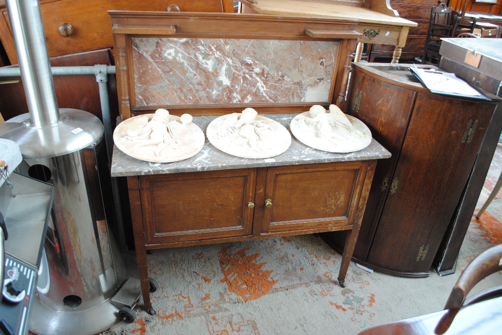 An Edwardian mahogany washstand with grey and white marble top and back over two crossbanded doors,