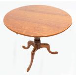 A late 19th century oak tilt top table with turned support to outswept tripod legs and pad feet,