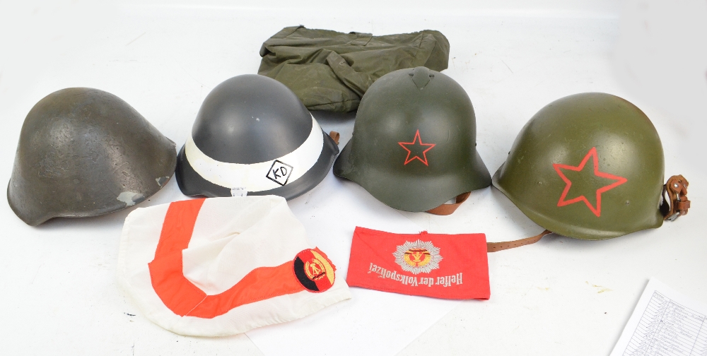 Four various helmets, three repainted with later decals, also an arm band.
