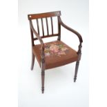 A Regency mahogany elbow chair, with reeded scrolling arms to turned and tapered legs,