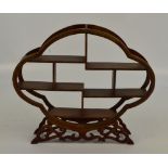 A modern hardwood netsuke display shelves of quadrilobed form, on foliate scroll base,