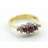 An 18ct yellow gold ring set with three graduated round cut rubies surrounded by twelve melee