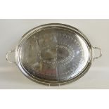 A large electroplated oval twin handled tray with concentric cut decoration centred on a crest of