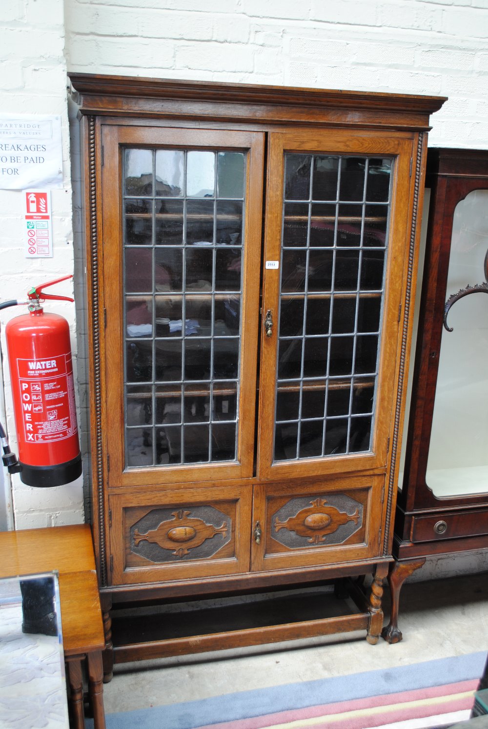 A 1920s oak and lead glazed display cabinet with twin panelled lower doors,