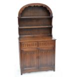 A reproduction oak dresser of two drawers including a cutlery drawer above two linen fold panel