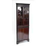 A mahogany corner cupboard with fretwork dentil cornice,