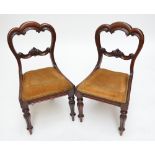 A pair of Victorian mahogany foliate scroll carved balloon back salon chairs on ring turned and