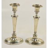 A pair of George V hallmarked silver loaded silver candlesticks with fluted tapering columns,