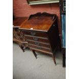An Edwardian music cabinet with raised back and four drawers, each with hinged front,