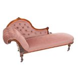 A Victorian walnut framed and button upholstered chaise longue raised on ring turned fluted legs.