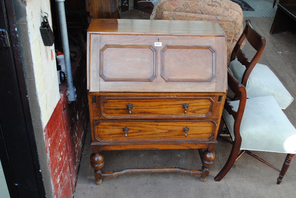 A 1930s oak geometrically moulded bureau with fitted interior and two long drawers, width 77cm.