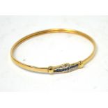 A 9ct yellow gold bangle set with central cornflower blue sapphires in a crossover diamond setting,