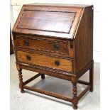 An early-to-mid 20th century oak bureau with two lower drawers to wrythen supports and cross