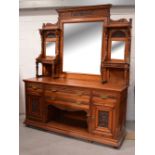 A c1900 carved oak mirror-back sideboard, carved pediment above central bevelled plate,