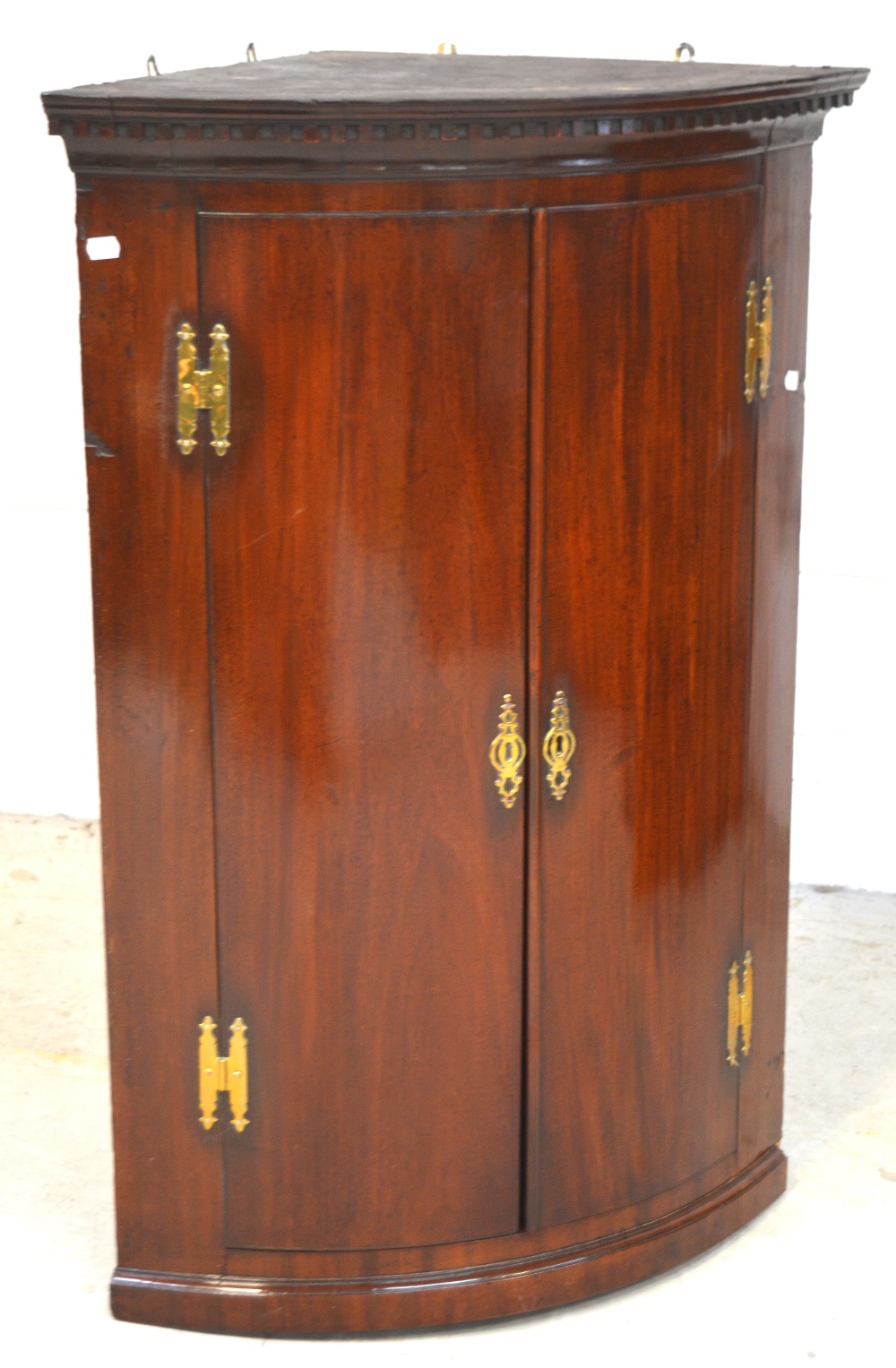 A George III mahogany bow-front corner cupboard, three shelves to interior,