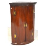 A George III mahogany bow-front corner cupboard, three shelves to interior,