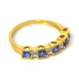 An 18ct yellow gold ring set with alternating emerald-cut sapphires and illusion-set diamonds in a