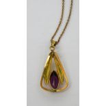 A yellow metal pendant set with marquise-cut purple stone on a curb link yellow metal chain,