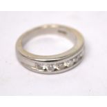 An 18ct white gold ring, channel set with seven diamonds, size M, approx 9.5g.