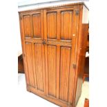 A mid-20th century Arts and Crafts style two-door wardrobe, carved frieze above carved panel doors,