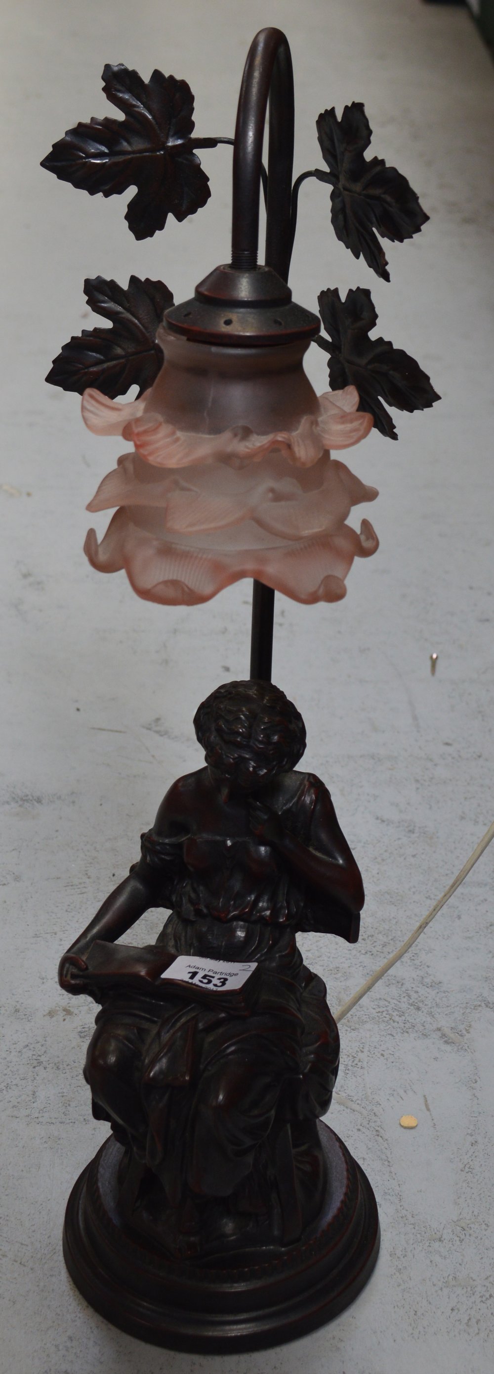 A vintage cut glass bag chandelier and a modern bronze-effect figural lamp with opaque pink glass