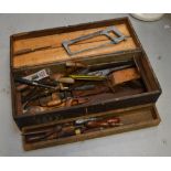 A vintage ebonised toolbox containing a quantity of tools to include chisels and saws.