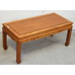 An Oriental hardwood coffee table, carved frieze on block supports, length 94cm.