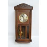 A 1940s oak wall clock with silvered dial set with Arabic numerals, length 79cm.