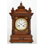 A 20th century mahogany mantel clock with carved stepped top with three finials,