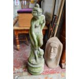 A reconstructed stone figure of an artfully draped naked maiden, on a circular plinth,