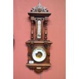 An Edwardian mahogany framed aneroid barometer with thermometer within a carved case.